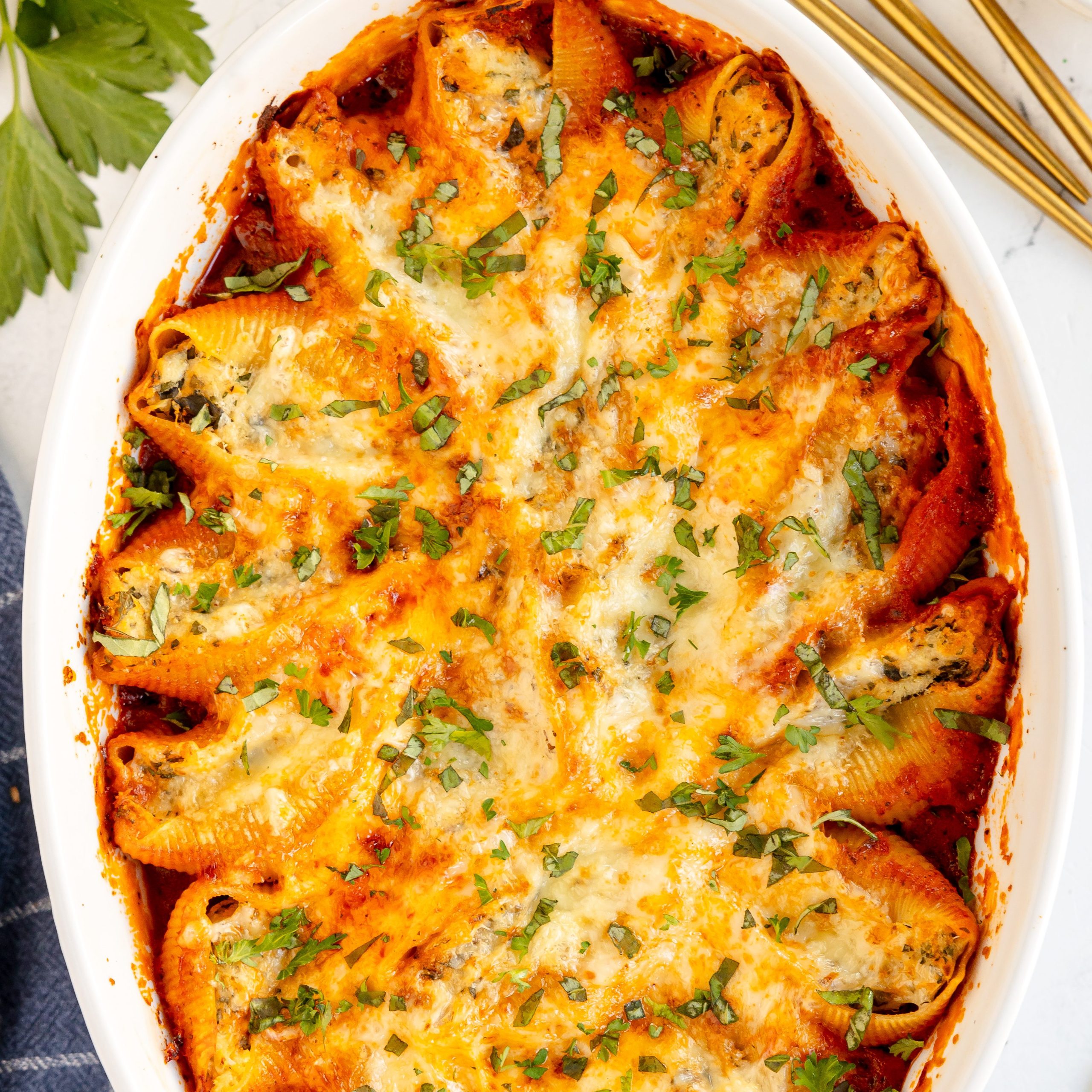 Overhead photo of chicken stuffed shells with creamy tomato sauce served in a white oval casserole dish.